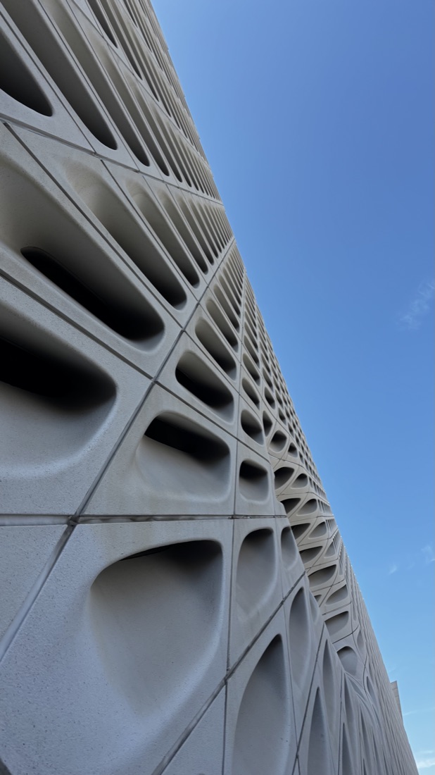Looking up a sculptural concrete facade against a blue sky