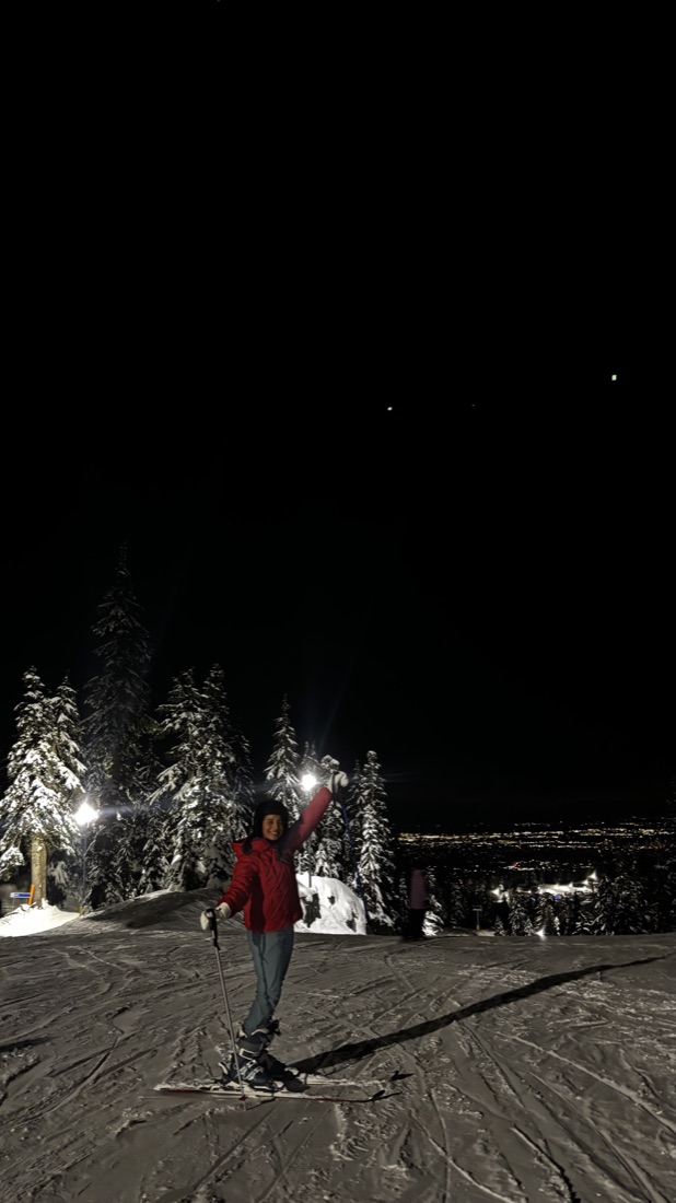 Night skiing on a snowy mountain with city lights below